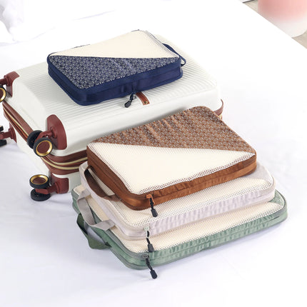 Caveri compression packing cubes in navy, tan, stone and sage stacked beside a white suitcase