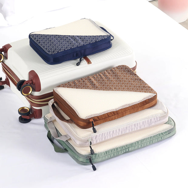Caveri compression packing cubes in navy, tan, stone and sage stacked beside a white suitcase