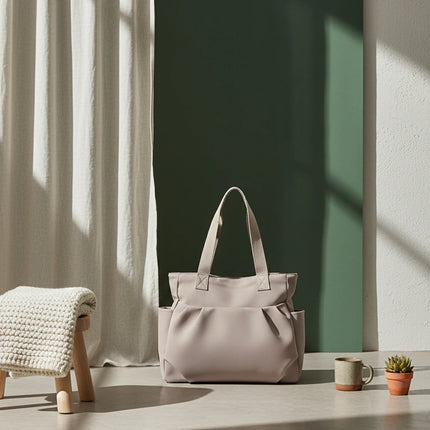 Caveri day bag in stone beige with structured handles, styled against a sage green backdrop