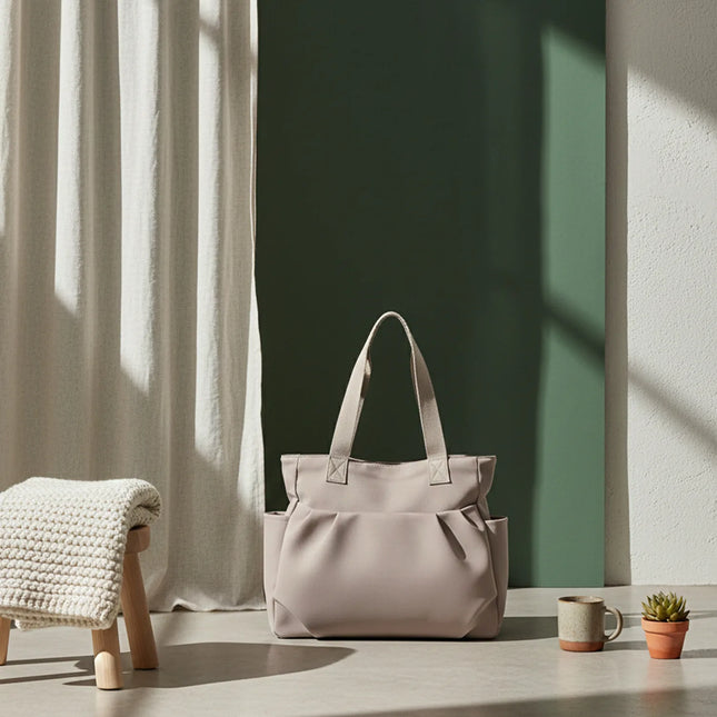 Caveri day bag in stone beige with structured handles, styled against a sage green backdrop