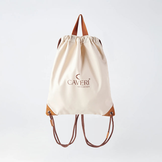 Caveri cream drawstring bag with tan leather corners and brown rope straps, front view
