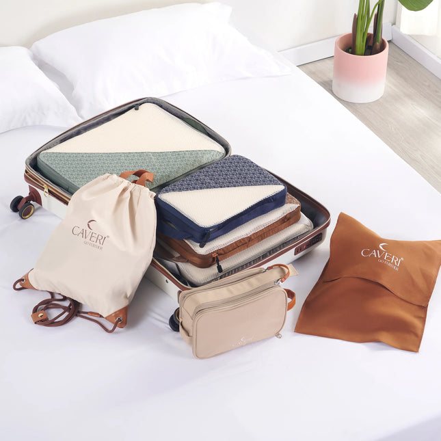 Caveri drawstring bag in cream beside open suitcase with packing cubes, toiletry bag and travel pillow on hotel bed