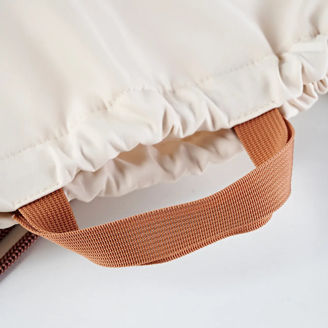 Caveri drawstring bag close-up showing elasticated opening and terracotta woven carry handle in cream
