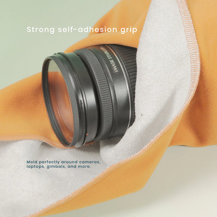 Caveri grip wrap in amber holding a camera lens, showing strong self-adhesion moulding around gear