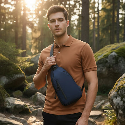 Man wearing Caveri navy sling bag cross-body on a forest trail at golden hour