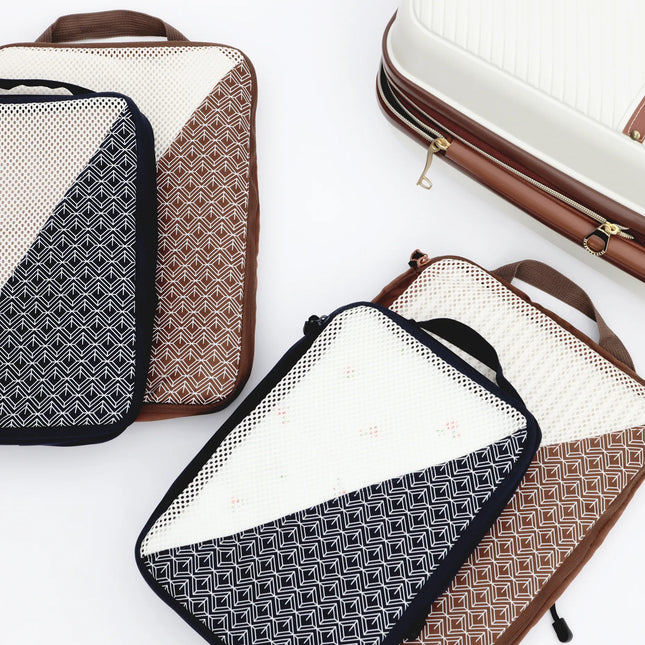 Caveri Nomad Kit packing cubes in navy and tan geometric print with mesh panels, styled with white hardcase luggage