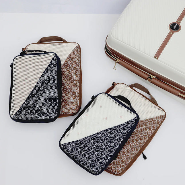 Caveri Nomad Kit packing cubes in navy and tan geometric print with mesh panels, styled with cream hardside luggage