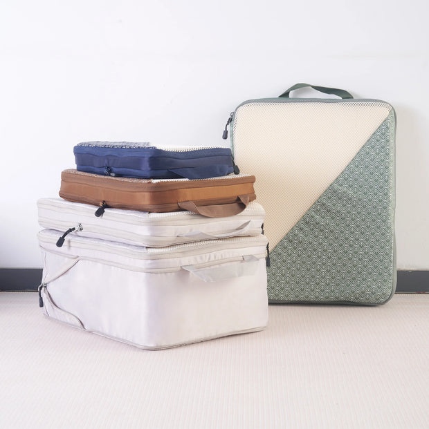 Caveri packing cubes set in sage green, white, tan and navy arranged by size