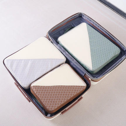 Four Caveri packing cubes in grey, green and tan organised inside an open suitcase, overhead view