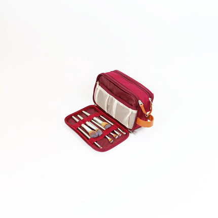 Caveri toiletry bag in berry red open to show brush holder panel and mesh pocket with tan leather handle