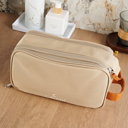 Caveri toiletry bag in sand beige with dual zips and tan leather handle on bathroom counter