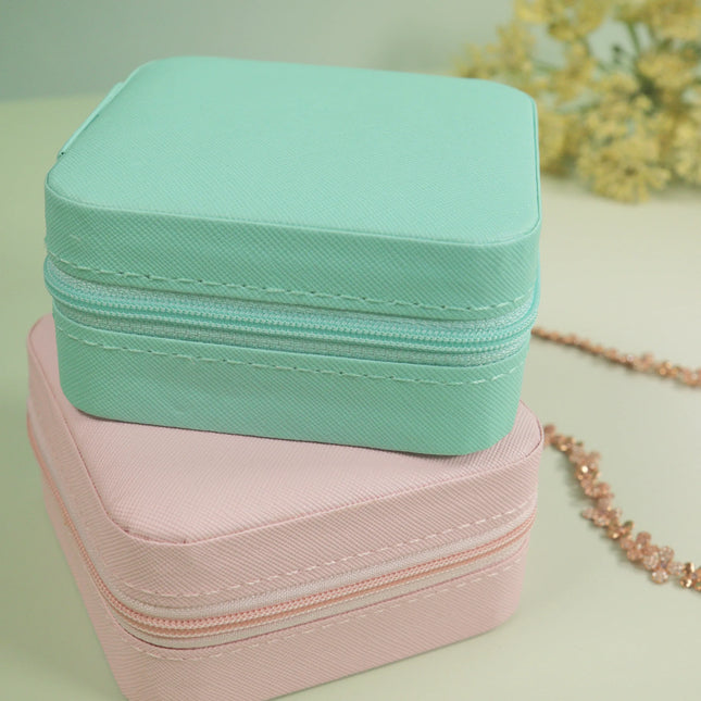 Caveri travel jewellery cases in mint and blush pink with zip closure, styled with gold necklace