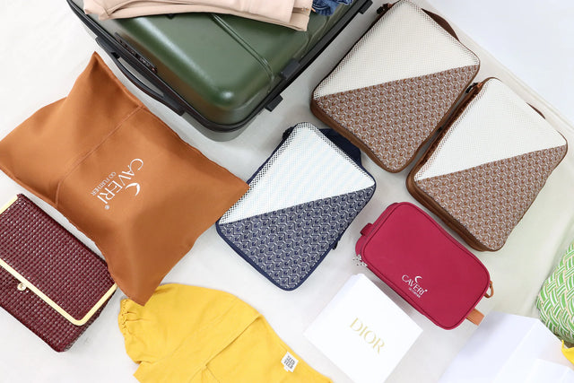 Caveri Wanderlust Kit with packing cubes, toiletry bag and laundry pouch laid out beside an open green suitcase