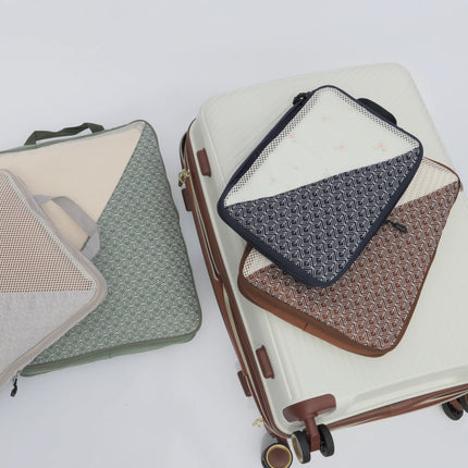 Caveri Wanderlust packing cube set in sage, navy and brown geometric print with mesh panels beside a white suitcase