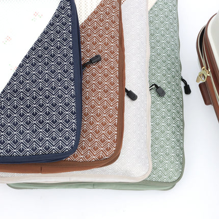 Caveri Wanderlust packing cubes in navy, tan, white and sage green with geometric print, stacked flat lay