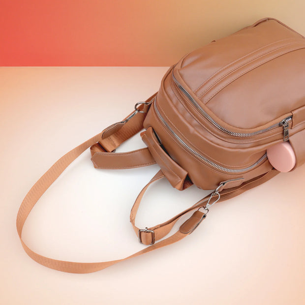 Caveri Zea mini backpack in tan with silver zips and adjustable shoulder straps, side view