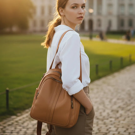 Woman wearing Caveri Zea day bag in tan leather as a backpack on a cobblestone path