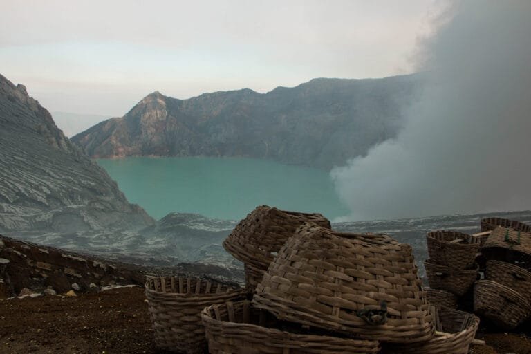 Empty woven baskets resting on rocky terrain at Kawah Ijen, ready to be filled with freshly mined sulphur