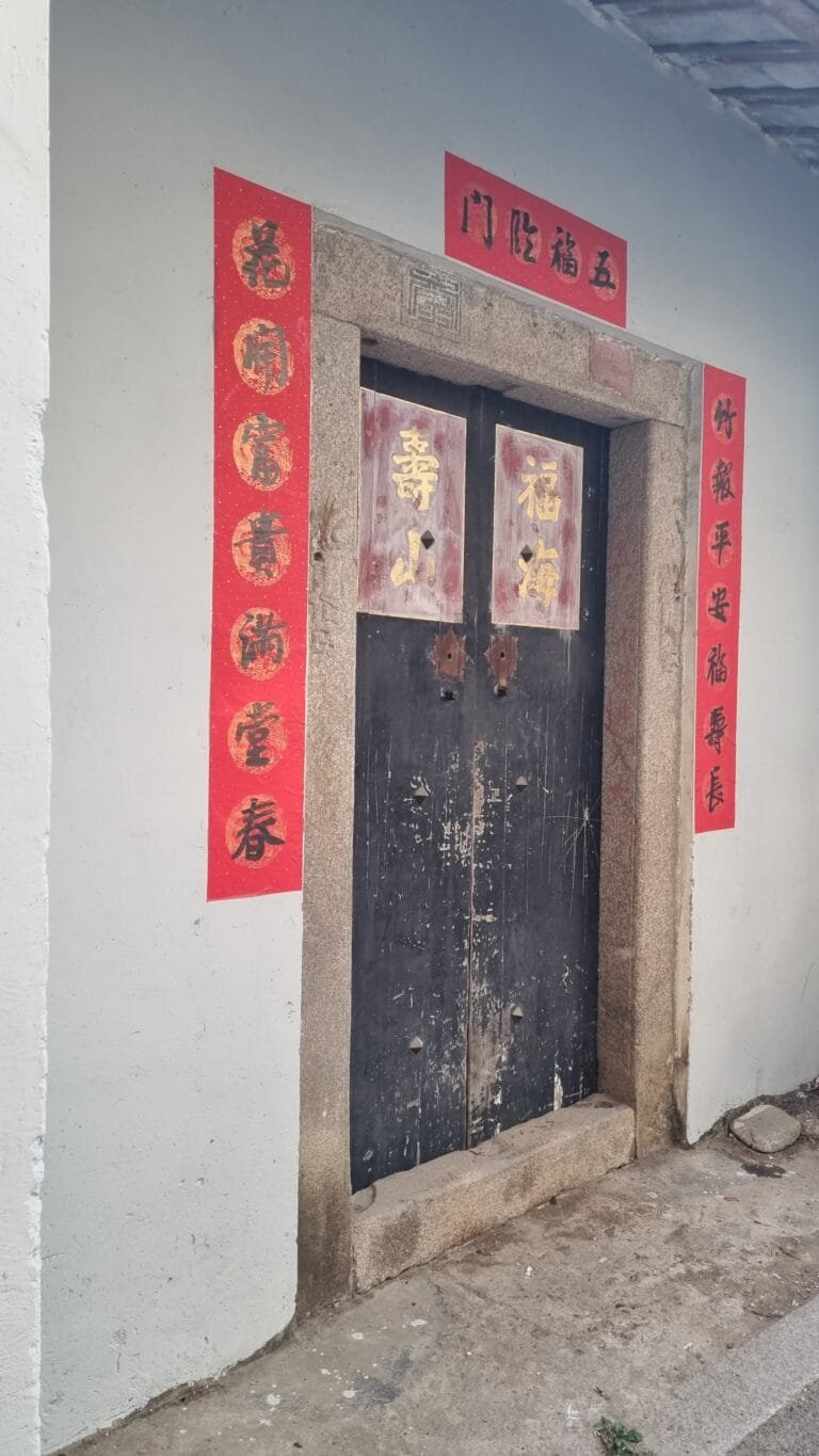 Traditional Chaozhou doorway with red blessing banners showing authentic Teochew cultural heritage and ancestral customs